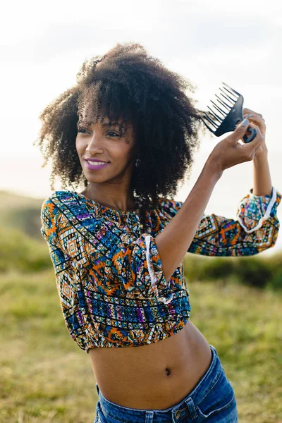 Mujer joven usando peine de pelo afro — Foto de Stock