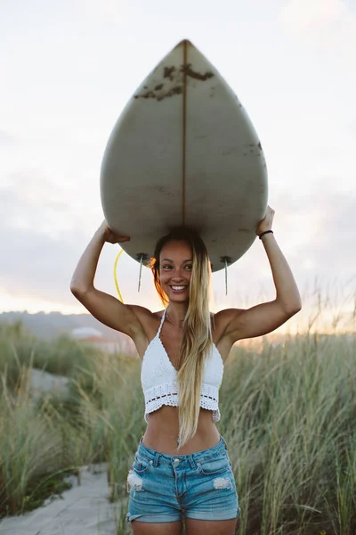 Vrolijke vrouw met surfplank op het strand — Stockfoto