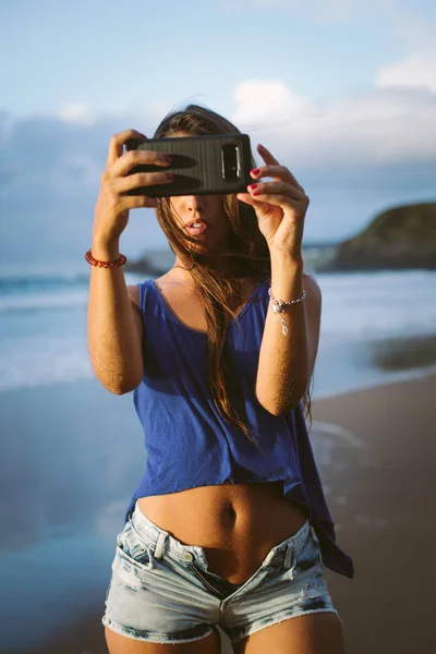 Vrouw maakt foto met smartphone op het strand — Stockfoto