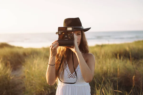 Hipster woman taking photos with an old instant analog camera in — Stock Photo, Image