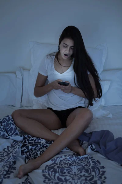 Menina sonolenta usando smartphone na cama — Fotografia de Stock