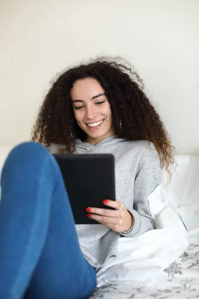 Chica casual leyendo en la tableta digital en la cama — Foto de Stock
