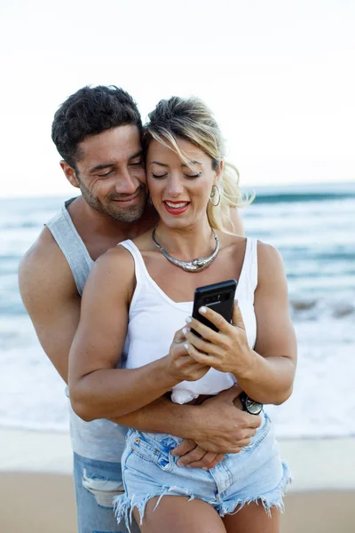 Jovem casal com smartphone na praia — Fotografia de Stock