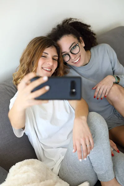 Νεαρό θηλυκό ζευγάρι στο σπίτι παίρνοντας selfie — Φωτογραφία Αρχείου