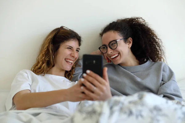 Duas mulheres na cama usando smartphone — Fotografia de Stock