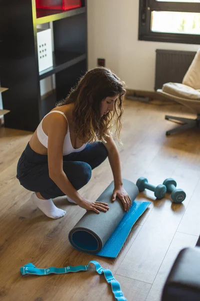 瑜伽室内锻炼时 年轻女子在客厅里滚动健身垫 积极和健康的生活方式概念 — 图库照片
