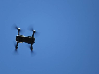 Arka planda mavi gökyüzü ile dört pervaneler ve kamera uçan profesyonel drone