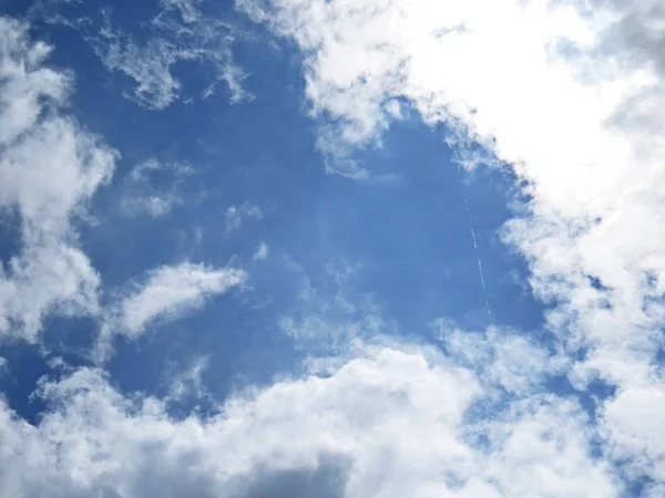 Beautiful White and Black Clouds on a Blue Sky with Sunlight in the Background