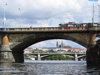 Arka planda bulut gökyüzü ile bir köprü altında seen Prag Kalesi Hradcany Panorama
