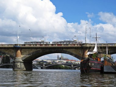 Arka planda bulut gökyüzü ile bir köprü altında seen Prag Kalesi Hradcany Panorama