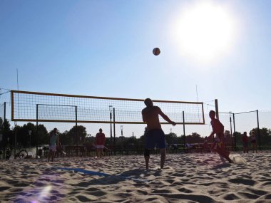 Sand Sunny Beach voleybolu erkekler arka planda top ve güneş ile oynuyor, Koszalin, Polonya, Ağustos 2018