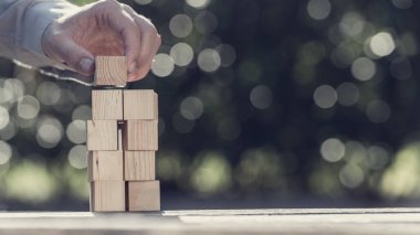 Adam açık havada yeşil karşı boş ahşap bloklar bir kule ile güneş ışığı parlak bokeh bina Retro tonlu görüntü.