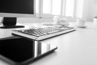 Yansımaları üstünde belgili tanımlık perde ile boş tablet, klavye ve masaüstü bilgisayar düşük açılı beyaz masa veya office tabloda görüntülemek.