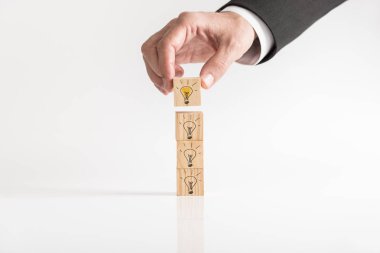 Işıklı ampul ahşap bloklar üzerinde beyaz bir tablo bir işadamı tarafından parlak fikir ve kopya alanı ile başarı kavramsal konuyor çizilmiş.