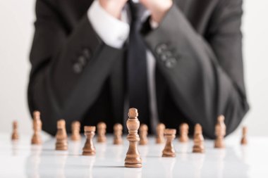 İş stratejisi Karanlık satranç figürleri ile beyaz masaya planlama iş takım elbiseli adamı.