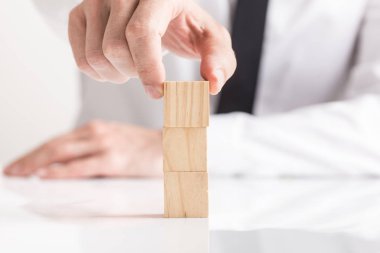 Üst üste, beyaz arka plan karşı yakın çekim görüntülenen boş tahta bloklar koyarak işadamı.