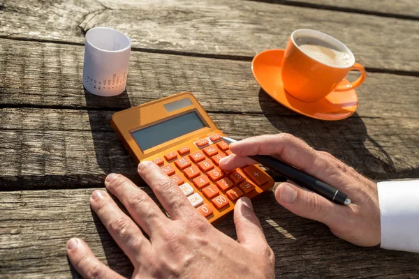 İşadamı kahve fincanı ve giriş yanındaki renkli portakal el ile hesap makinesi kullanma.