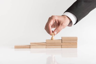 Kariyer yönetimi ile piyon satranç parça ahşap tuğla bir merdiven üzerinde beyaz arka plan üzerinde yerleştirerek bir işadamı kavramsal görüntü.