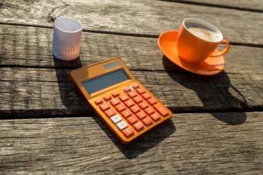 Kahve fincanı ve eski kırık ahşap masa alış irsaliyesinde yanında renkli portakal el ile hesaplama.