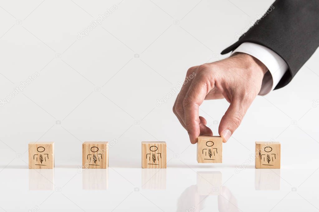Businessman hand arranging wooden blocks with small people images  team building concept against white background with copy space