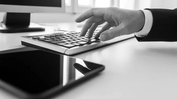Monochrome Image Businessman Typing Computer Keyboard Office Blank Tablet Foreground — Stock Photo, Image
