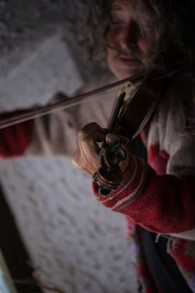 彼の目と屋内で古典的なバイオリンを弾いて古いセーターで巻き毛を持つ年配の男性を閉じる — ストック写真