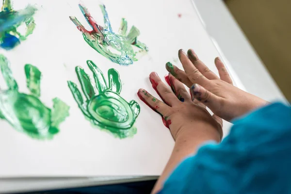 Мальчик Рисует Руками Разноцветные Отпечатки Ладоней Листе Бумаги — стоковое фото