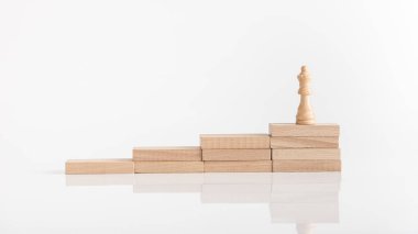 Kraliçe satranç taşını kopya alanı ile başarı kavramı bir yansıtıcı beyaz yüzey üzerinde ahşap blokların basamaklı bir yığın üzerinde.