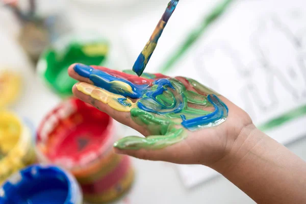 Bambino Dipingendo Sua Mano Con Pennello Con Vernice Colorata Una — Foto Stock