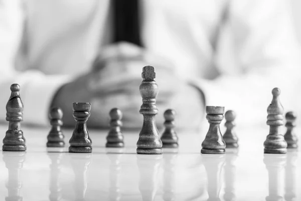 Монохромне Зображення Бізнесмена Сидить Перед Темними Шаховими Фігурами Білим Столом — стокове фото
