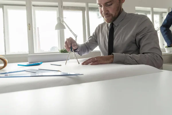 グレーのシャツ 黒のネクタイを取り組んでいる設計事務所のテーブルでの男 — ストック写真