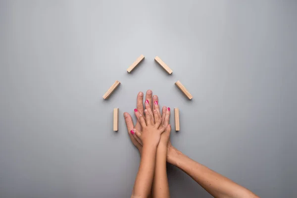 Mãos Pais Duas Crianças Dentro Quadro Uma Casa Fundo Cinza — Fotografia de Stock