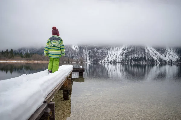 Вид Ззаду Дитини Зеленому Зимовому Костюмі Стоїть Засніженому Пірсі Озері — стокове фото