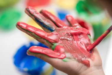 Kalın kırmızı el boya ile boyanmış bir yürümeye başlayan bir avuç closeup.