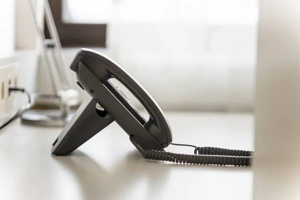 黑色座机电话在白色办公桌与模糊的背景 — 图库照片