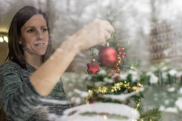 Vista Através Uma Janela Uma Jovem Mulher Colocando Bola Natal — Fotografia de Stock