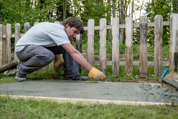 Diy Koncept Mladý Muž Vyrovnání Čerstvá Betonová Podlaha Palicí Jeho — Stock fotografie