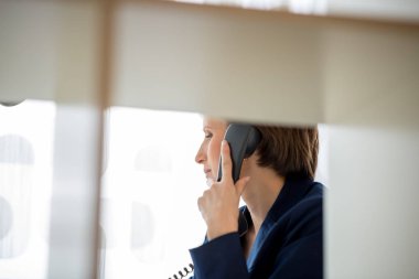Bir office bölüm siyah sabit hat telefon görüşmesi bir genç iş kadını, üzerinden görüntülemek.