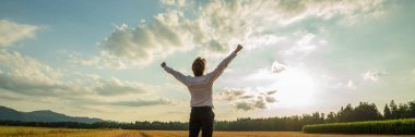 Panoramik görüntü başarılı işadamı yüksek zafer kaldırdı kollarını ile görkemli gökyüzü altında duran.