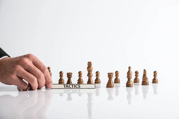 チェス駒の前に戦術サインを持ってビジネス リーダーが反射白い机の上に配置 — ストック写真
