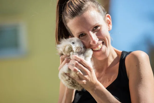 Mujer Sonriente Mirando Cámara Sosteniendo Conejo Bebé Sus Manos Afuera — Foto de Stock