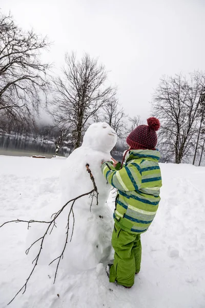 Junge Mit Strickmütze Bastelt Einen Winterschneemann Einer Verschneiten Landschaft — Stockfoto