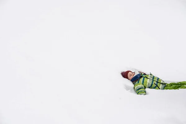 幼儿男孩有乐趣躺在右边的形象在新鲜的雪笑 具有复制空间 — 图库照片