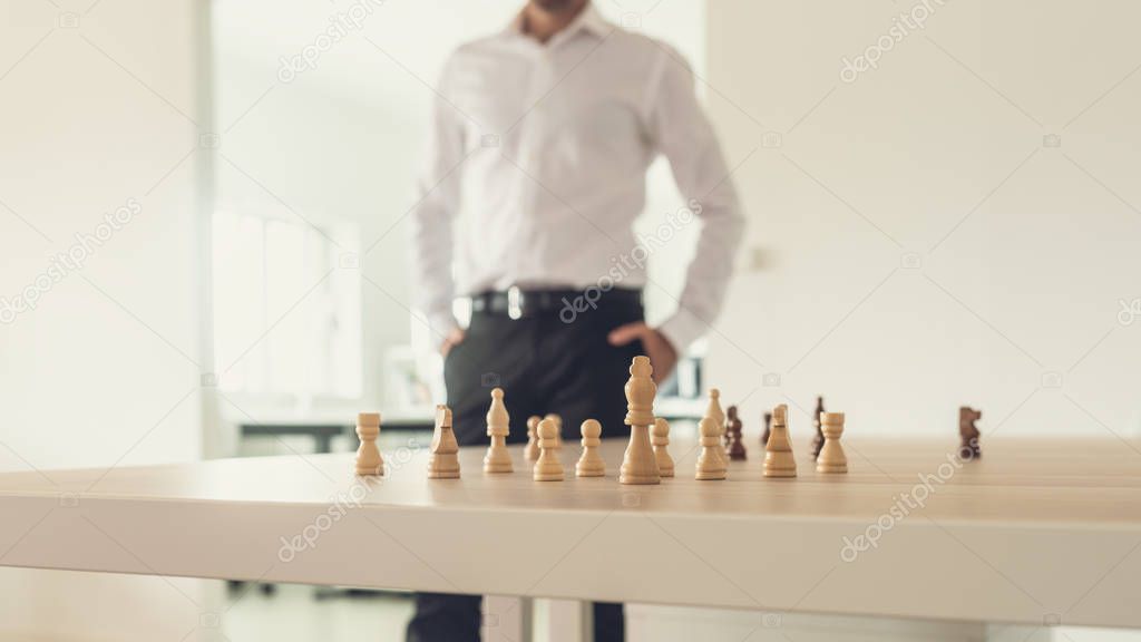 Retro image of a businessman standing proud next to his office desk with chess figures on it and king peace set as the leader.