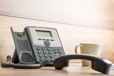 Siyah Sabit hat telefon telefon hattından ahşap ofis masası ve kahve kupa yanında tarih ile.