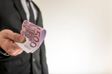 Beş yüz Euro faturaları bir resmin sağ tarafında kopya alanı bol olan sunan bir iş adamı. Kavramsal iş rüşvet ve finans.