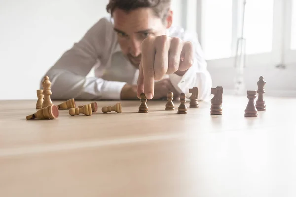 Business executive making strategy for the future by positioning black and white chess figures against each other with most of the whites fallen. With lens flare.