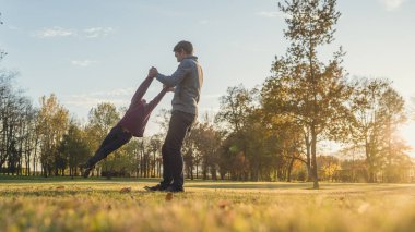Babası onu tarafından sonbahar parkı dışında onun ellerinde tutarak yürümeye başlayan çocuk oğlu iplik.