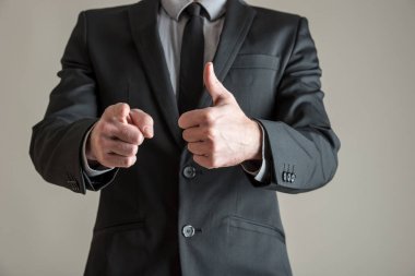 Bir başparmak yukarıya tek elle jest yapma ve onun parmak sana işaret ile diğer iş yürütme önden görünümü. Gri arka plan üzerinde.