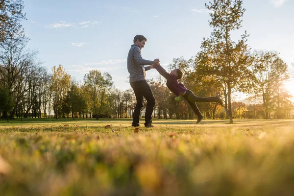 幸せな若い父秋の公園での外の彼の手によって彼を保持している彼の幼児の息子を回転 — ストック写真